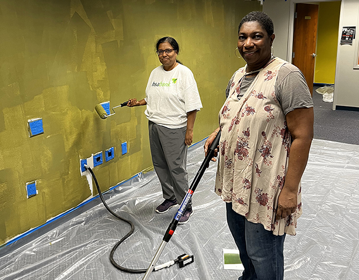 two HSA Bank volunteers painting a wall in an office